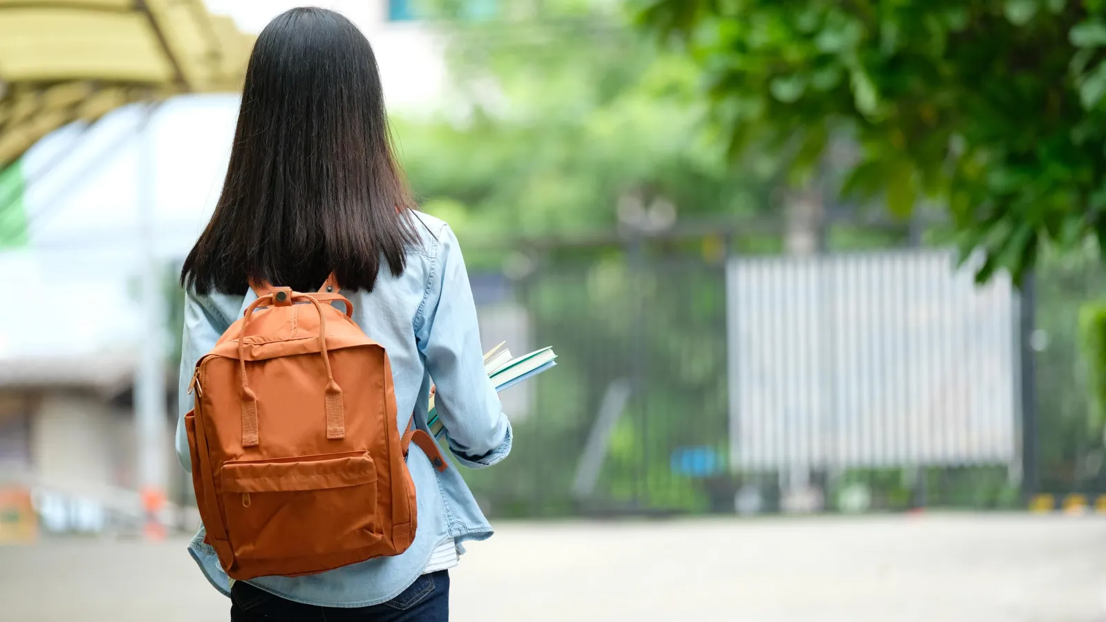 Mädchen mit Schulrucksack, abgewendet von der Kamera