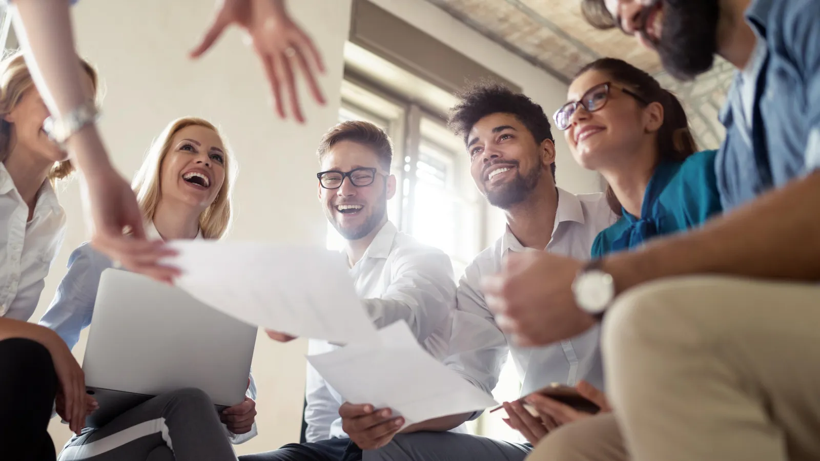 Studierende sitzen in einem Kreis in Arbeitsatmosphäre und lachen