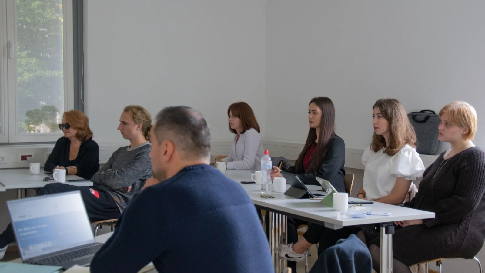 Lehrende und Teilnehmende der Summer School besprechen Präsentationen im Seminarraum.