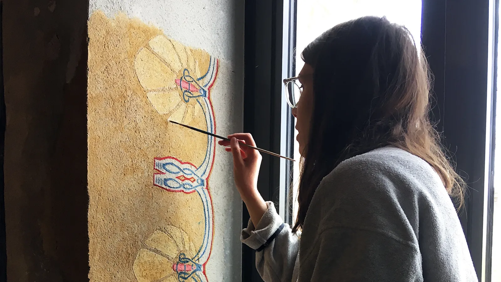 Studentin beim Malen an der Wand des Studentencafes.