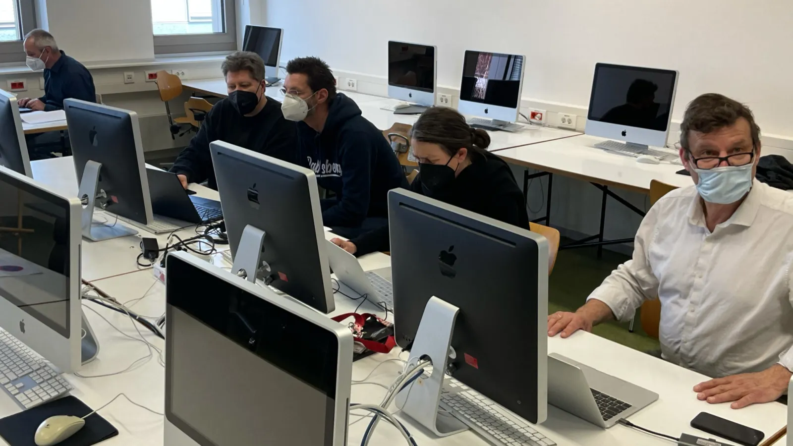 Teilnehmende des Workshops sitzen im Computerraum und arbeiten an Laptops und PCs.