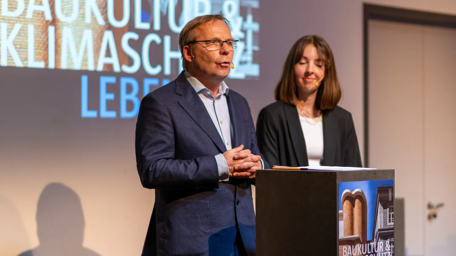 Die Moderator*innen Rudolf Spindler und Hannah Höpfner eröffnen die Veranstaltung "Baukultur und Klimaschutz leben"