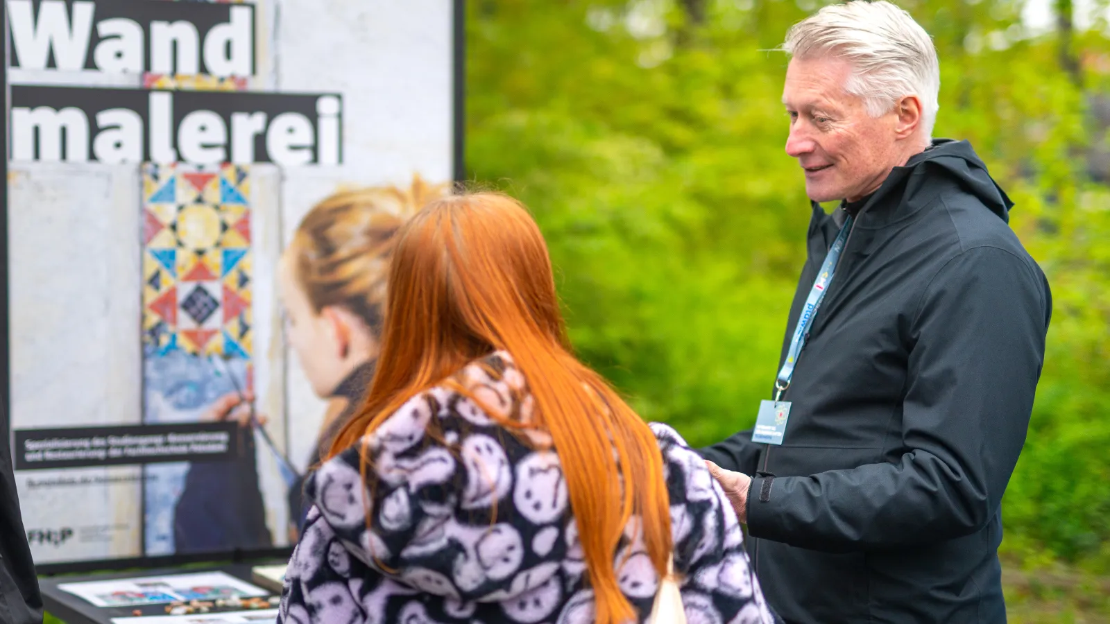 Prof. Dr. Steffen Laue bringt einer Besucherin beim Potsdamer Tag der Wissenschaften 2023 die Wandmalerei näher