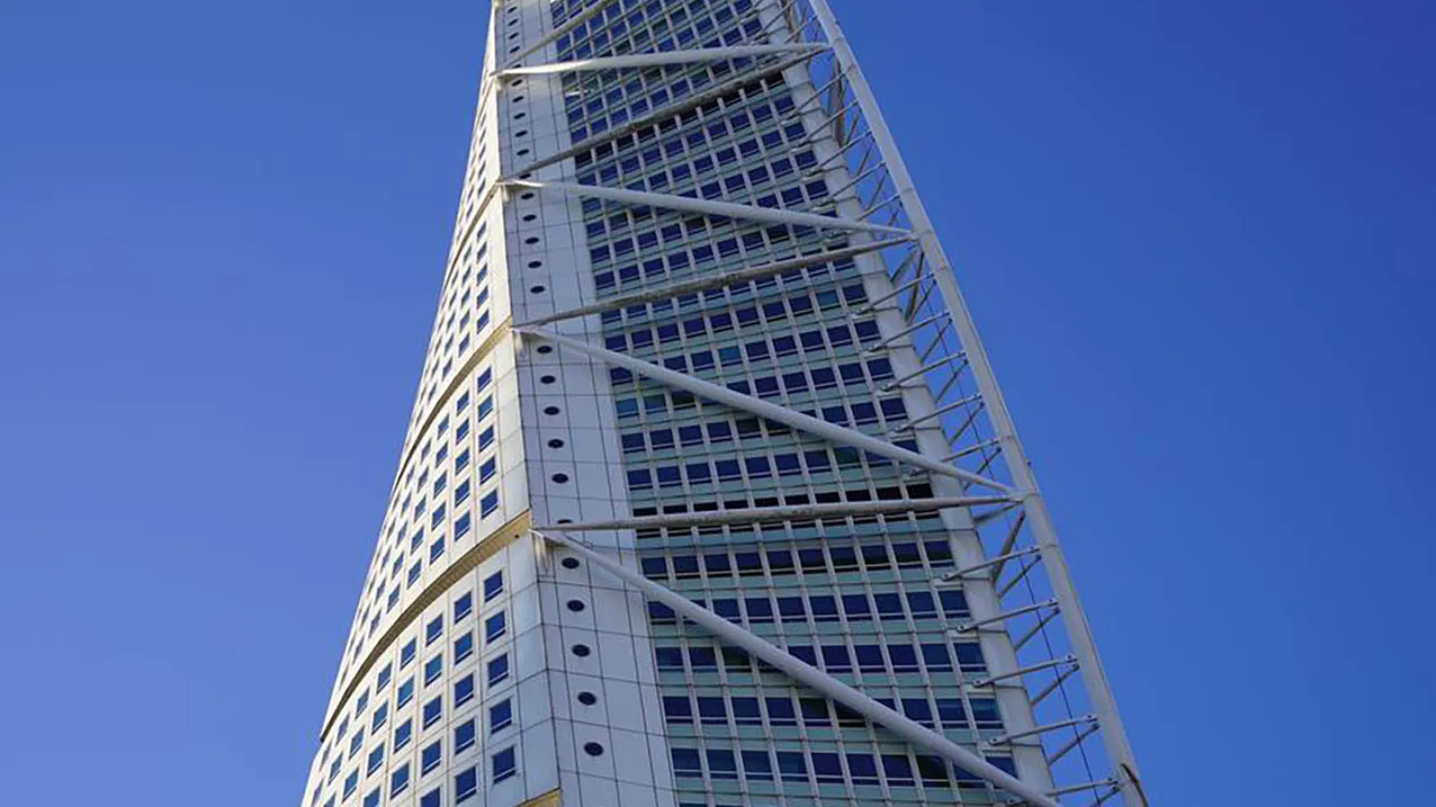 Ein weißes Hochhaus ragt in die Höhe. Der Himmel dahinter is ganz blau. 