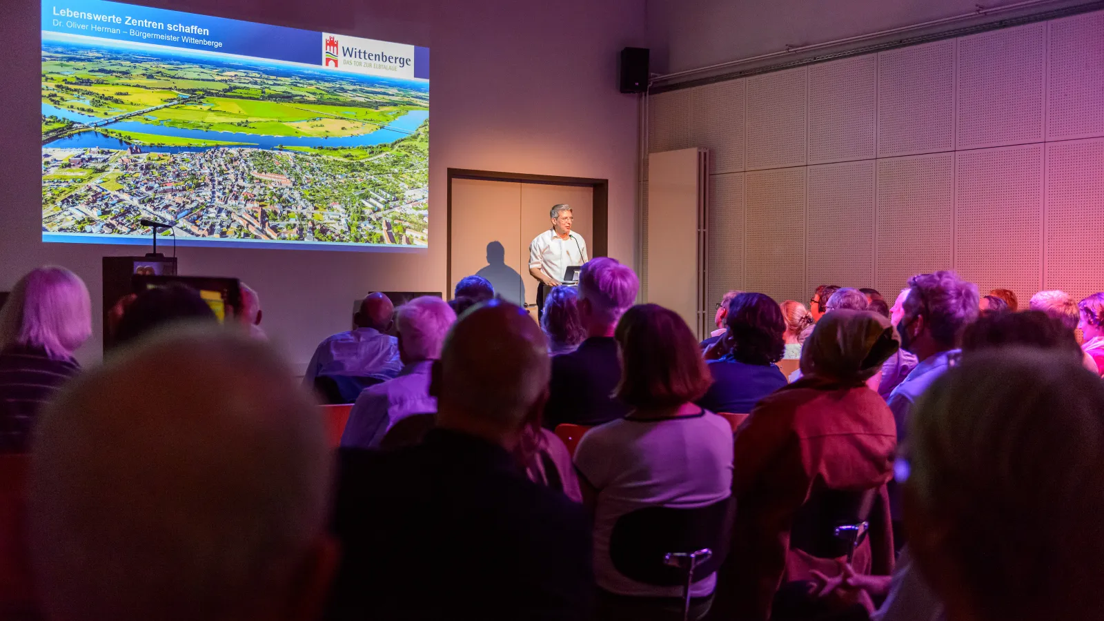 Dr. Oliver Hermann, Bürgermeister der Stadt Wittenberge (Prignitz), hält seinen Vortrag zum Thema "Lebenswerte Zentren schaffen in der Stadt Wittenberge" vor vielen interessierten Besucher*innen der 3. Veranstaltung der Reihe Baukultur und Klimaschutz leben