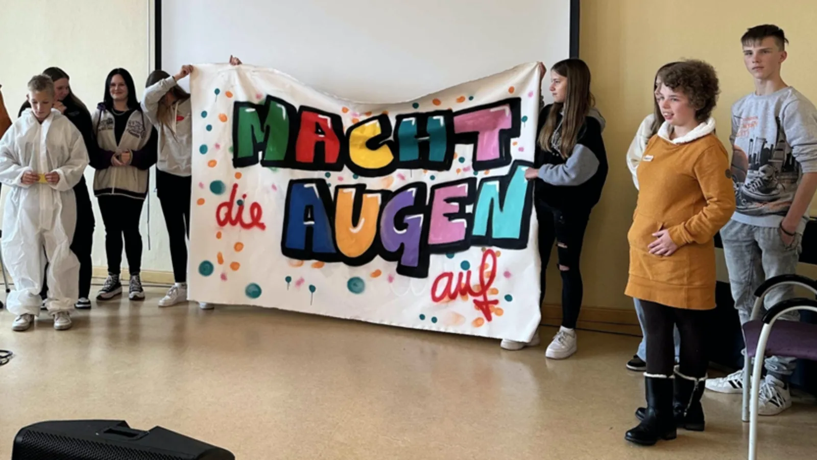 Schüler*innen von Wittenberger Schulen halten ein Plakat mit dem Motto "Macht die Augen auf"