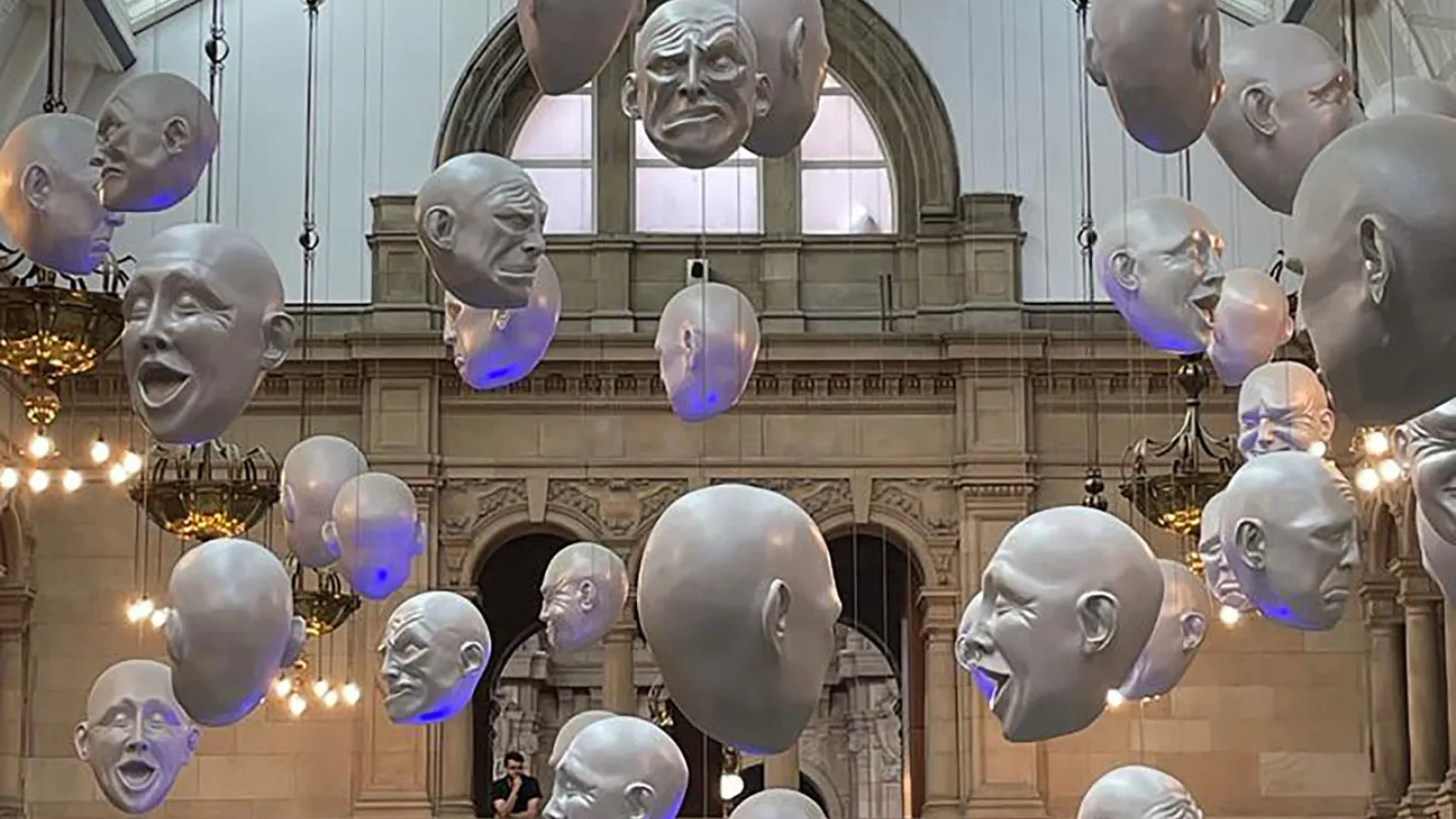 Im Klevingrove Art Gallery hängen weiße Köpfe aus Kunststoff an Schnürren von der Decke. Jeder Kopf hat einen anderen verzogenen Gesichtsausdruck.