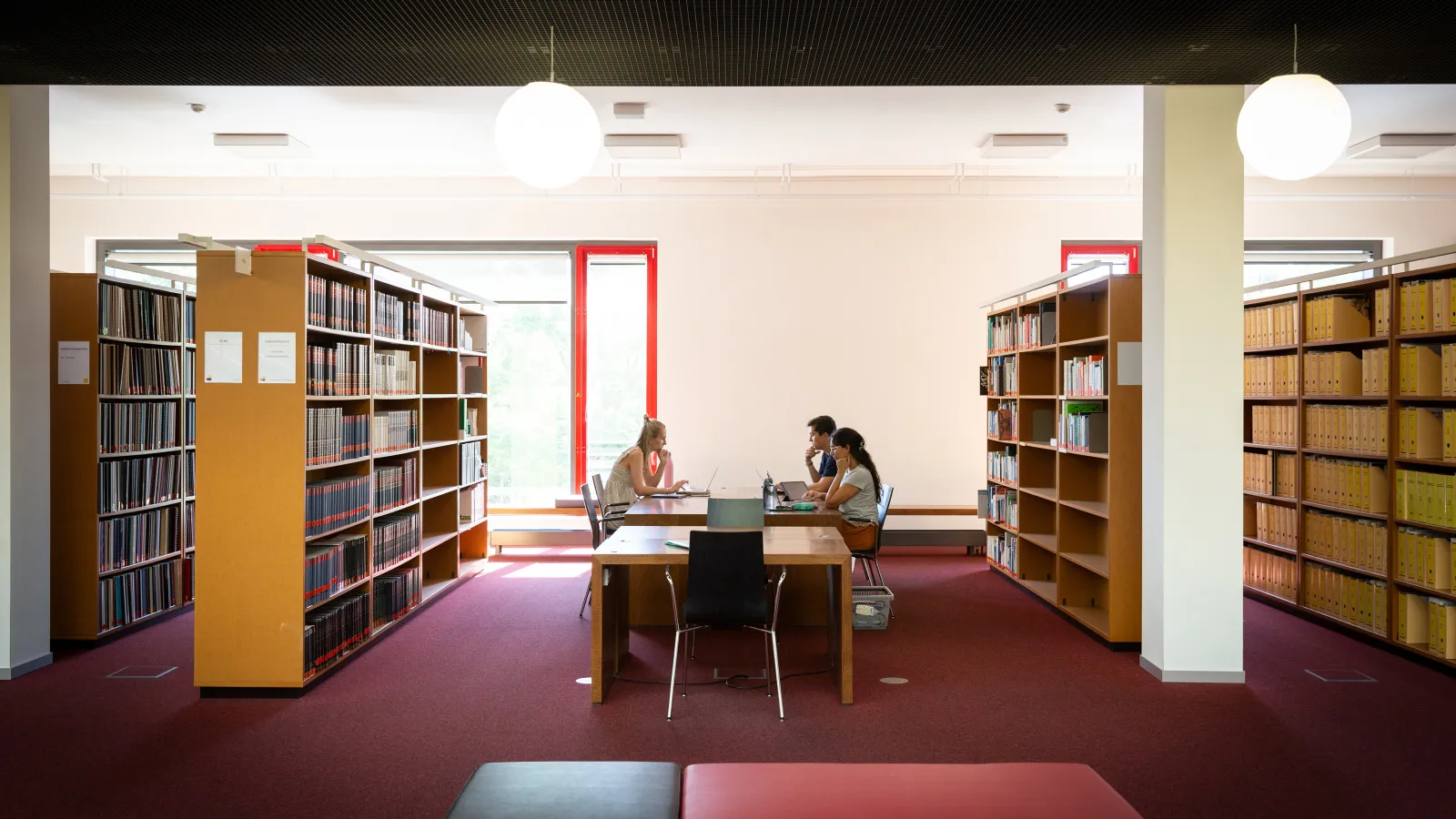 Studierende sitzen in der Bibliothek an einem Tisch