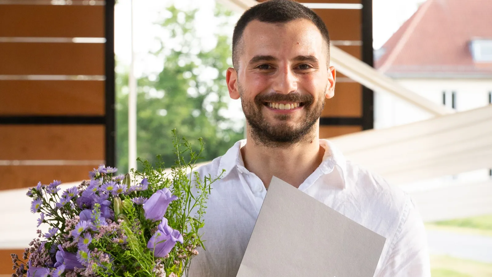 DAAD-Preisträger Hadi Daaboul mit Blumenstrauss und Urkunde