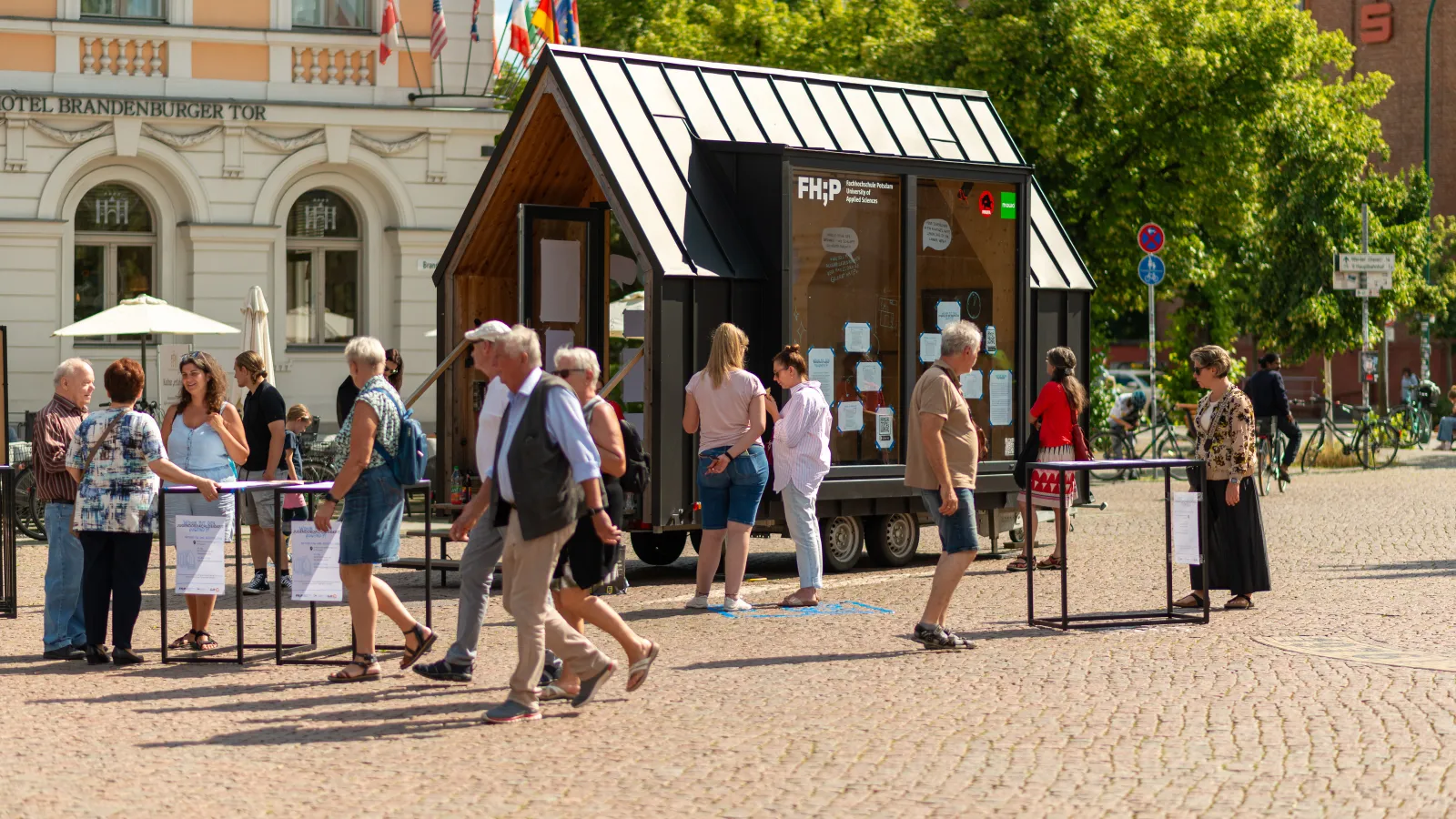 Interessierte Besucherinnen und Besucher unterhalten sich mit Studierenden der FHP zum Thema "Wohin mit der Jugend" vor dem FHP Mobil in der Potsdamer Innenstadt