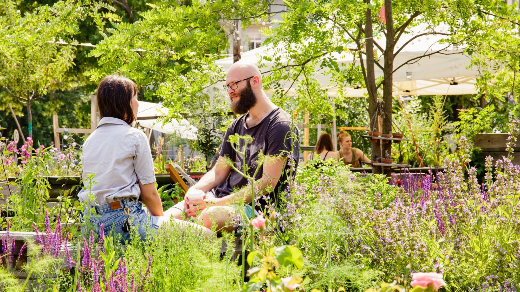 Studierende im Campusgarten sprechen zueinander