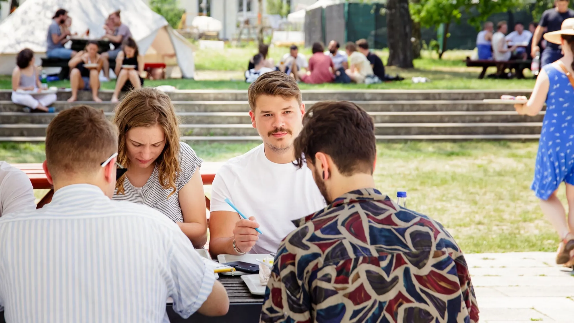 Studierende vor der Mensa lernen gemeinsam an einem Tisch