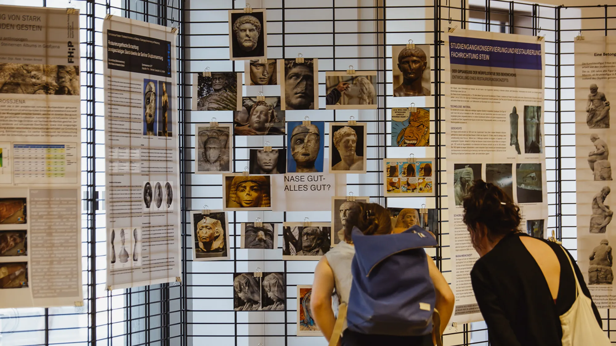 Zwei Personen schauen sich Fotos von Steinskulpturen an