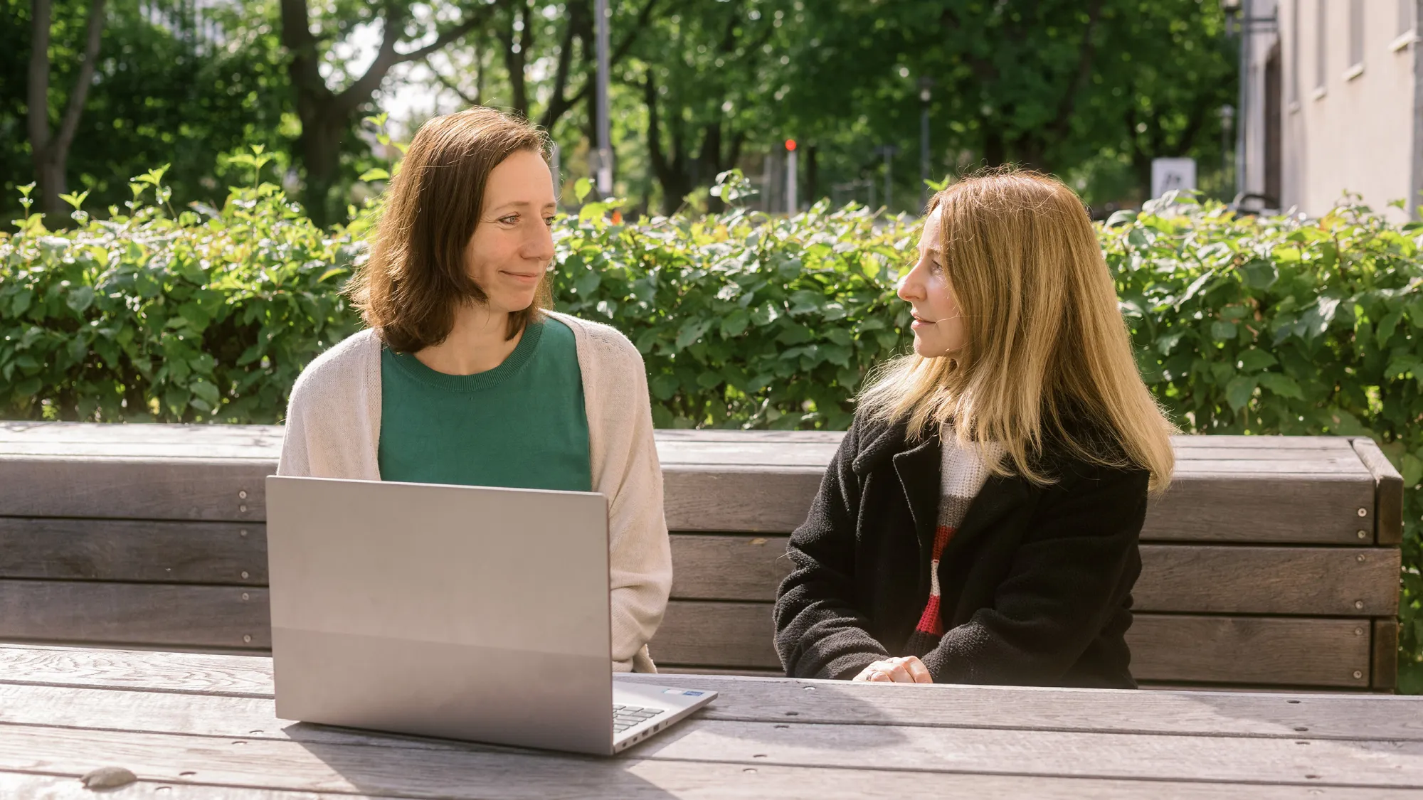 Stephanie Teichler und Prof. Dr. Schmidt-Wenzel sitzen an einem Holztisch auf dem Campus