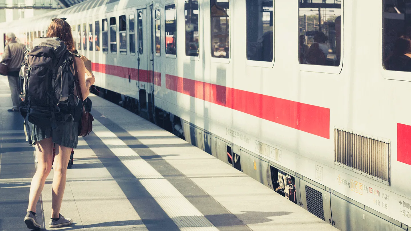 Person mit Rucksack am Gleis Zug Deutsche Bahn