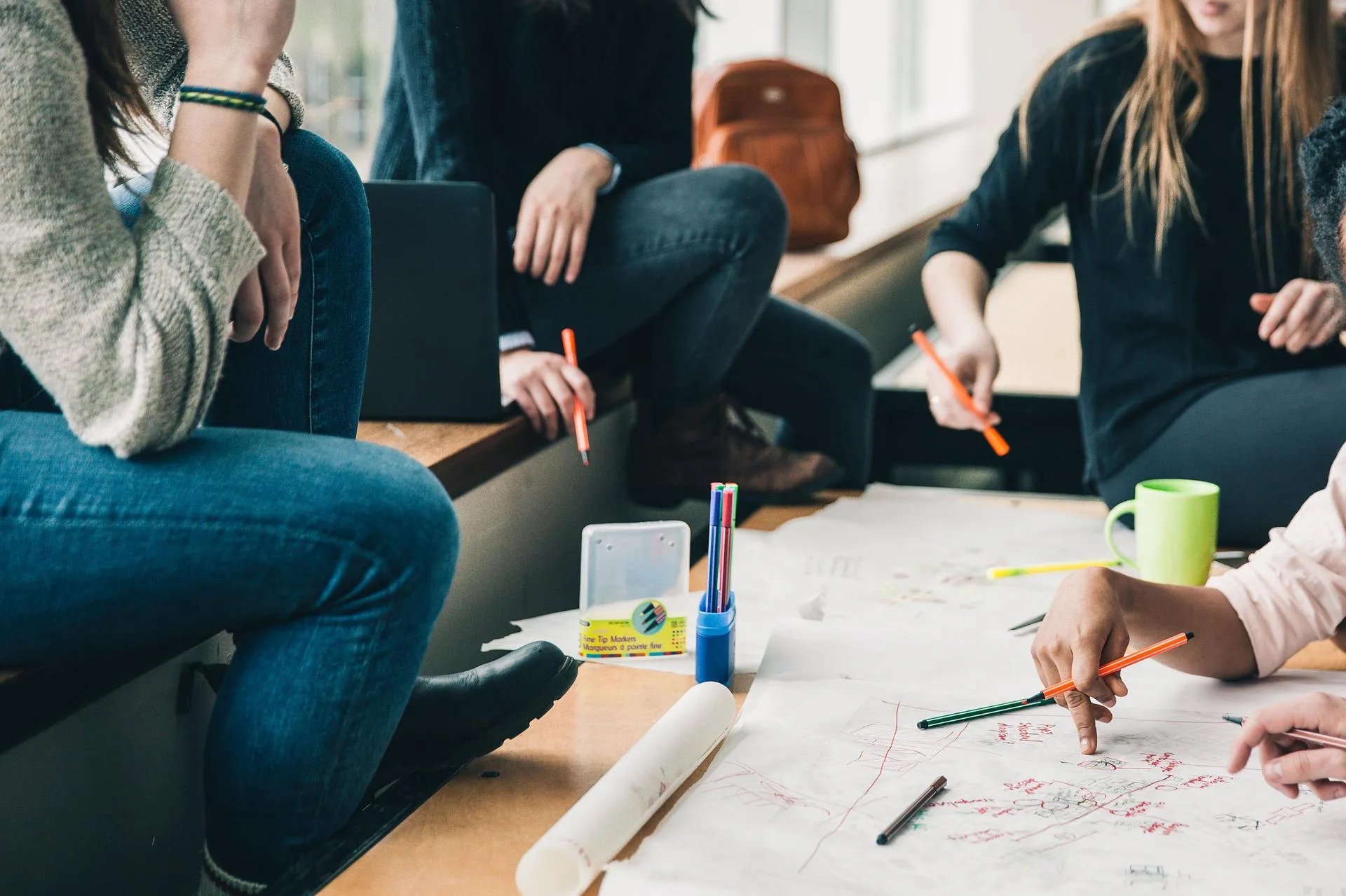 Mehrere Menschen sitzen leger am Tisch und arbeiten gemeinsam an einem Projekt