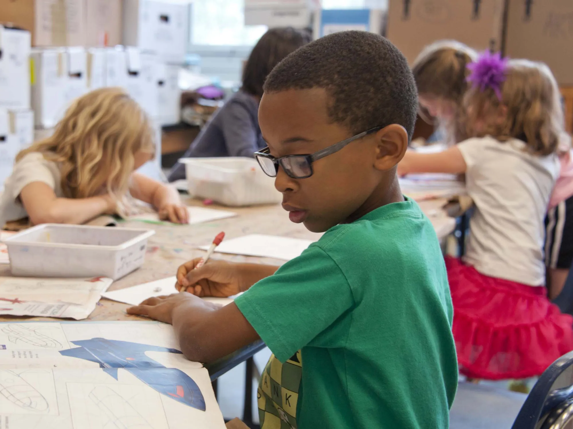 Kinder sitzen an einem Tisch und arbeiten in Heften