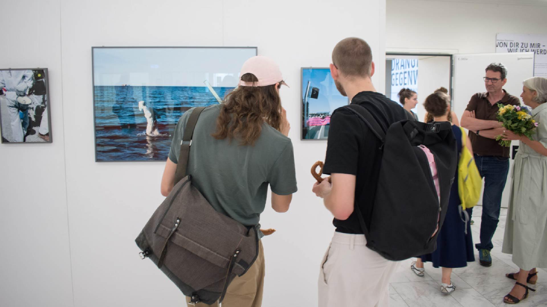 Zwei Personen schauen auf ein eingerahmtes Bild in einem Ausstellungsraum