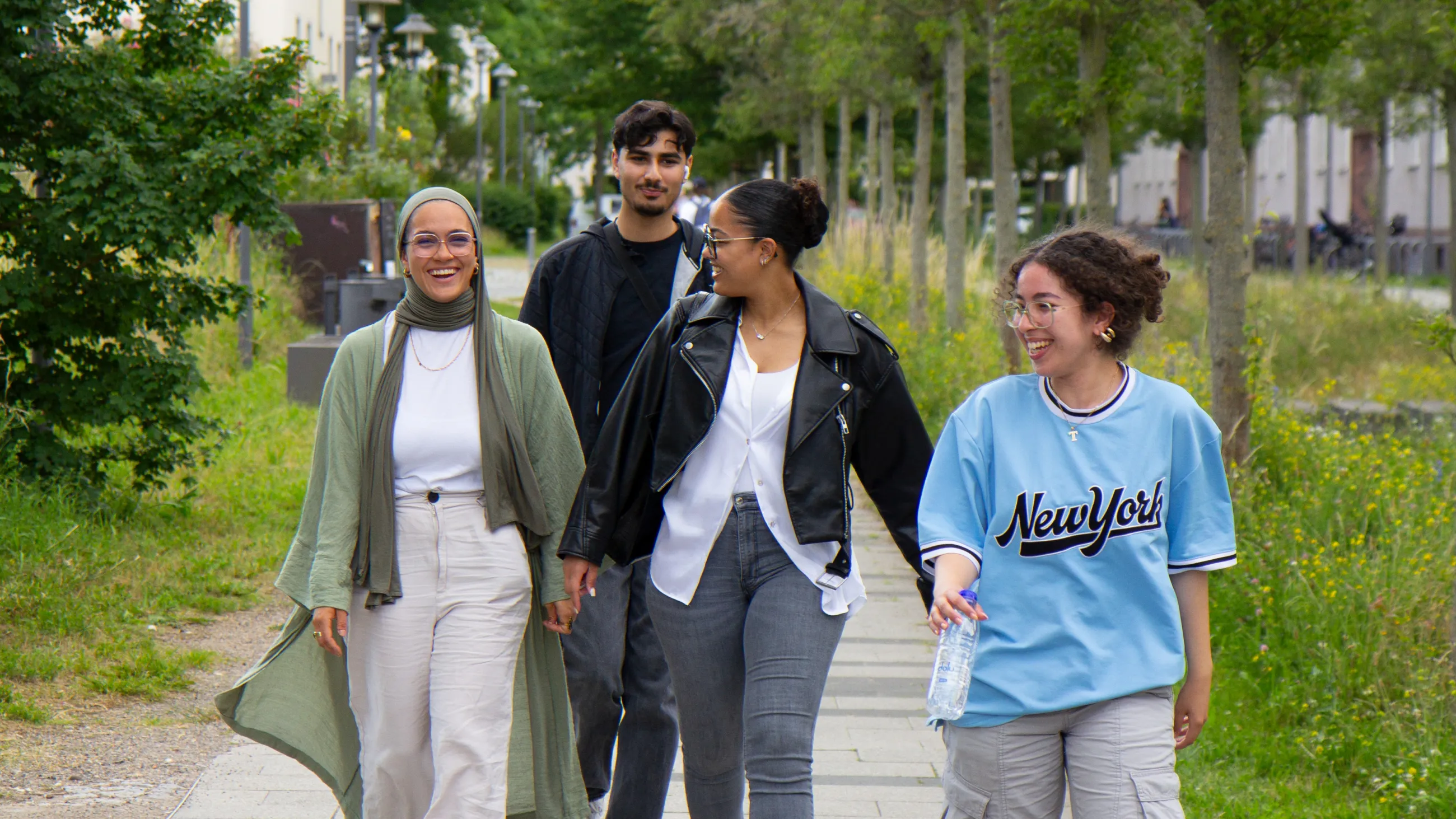 Vier Studierende laufen fröhlich über den Campus