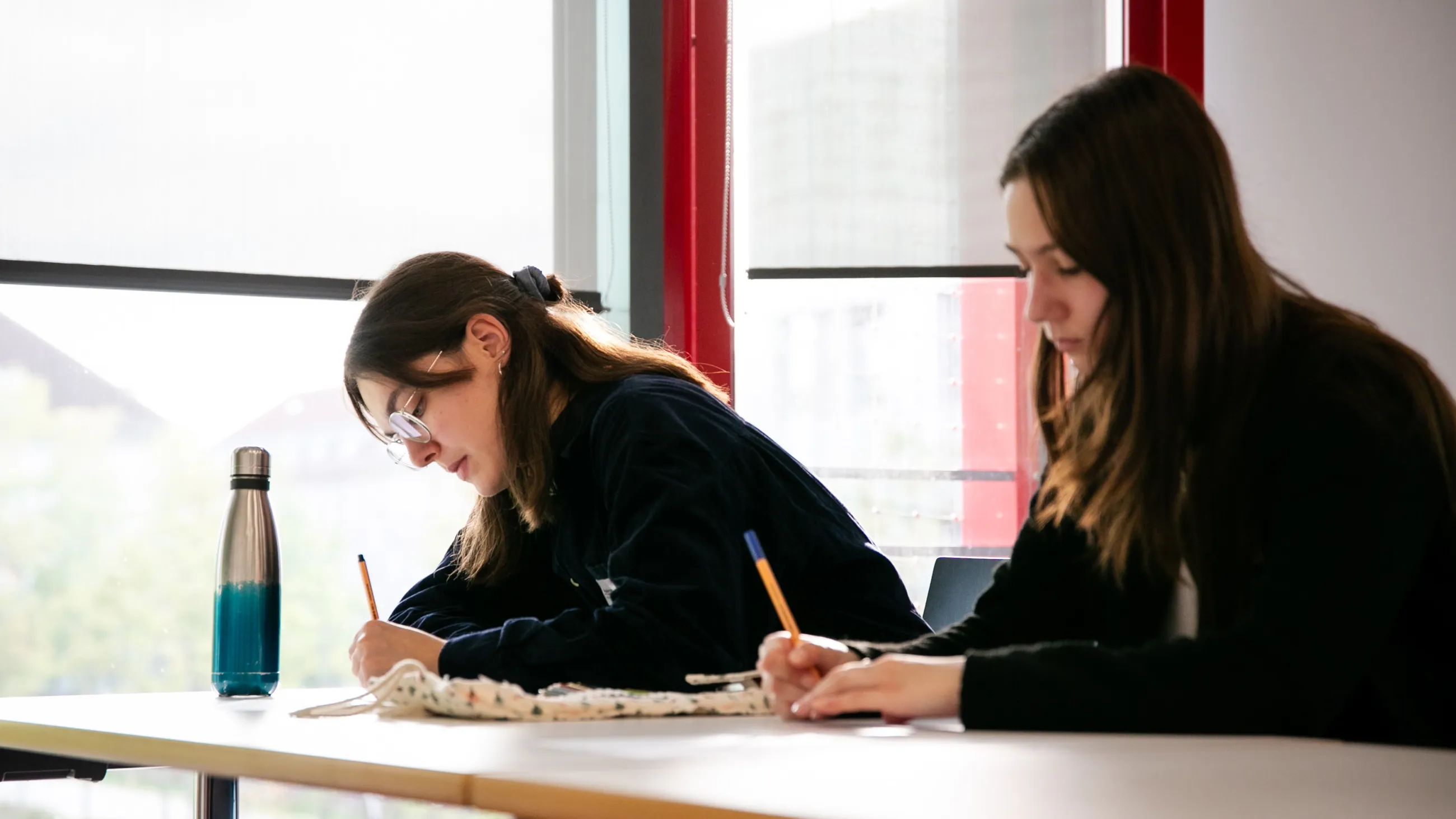 Zwei Studierende notieren etwas auf Papier