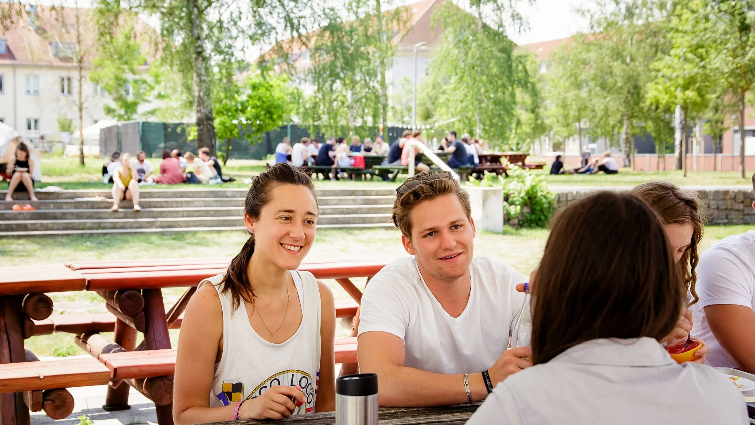 Zwei Studierende vor der Mensa im Tischgespräch