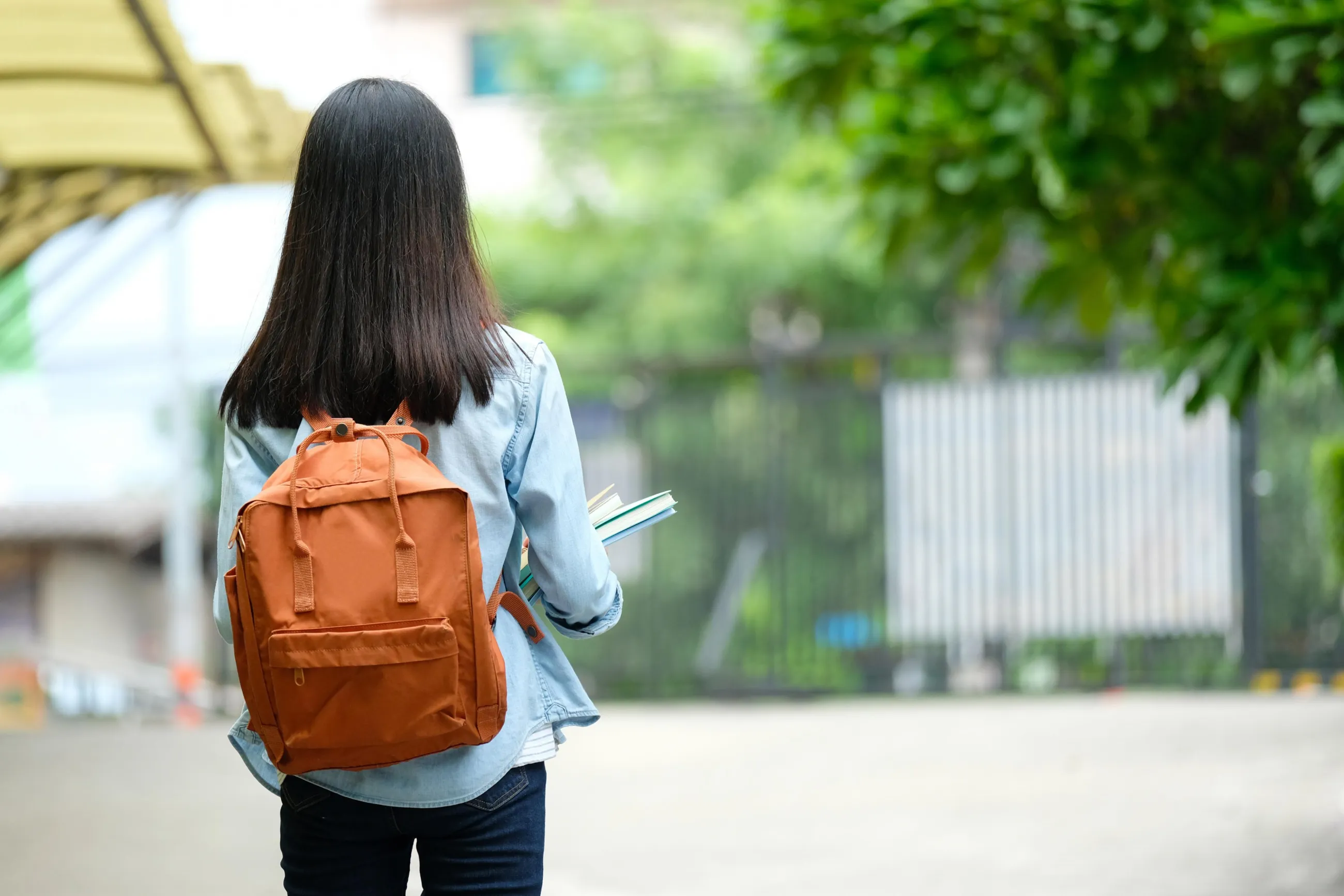 Mädchen mit Schulrucksack, abgewendet von der Kamera